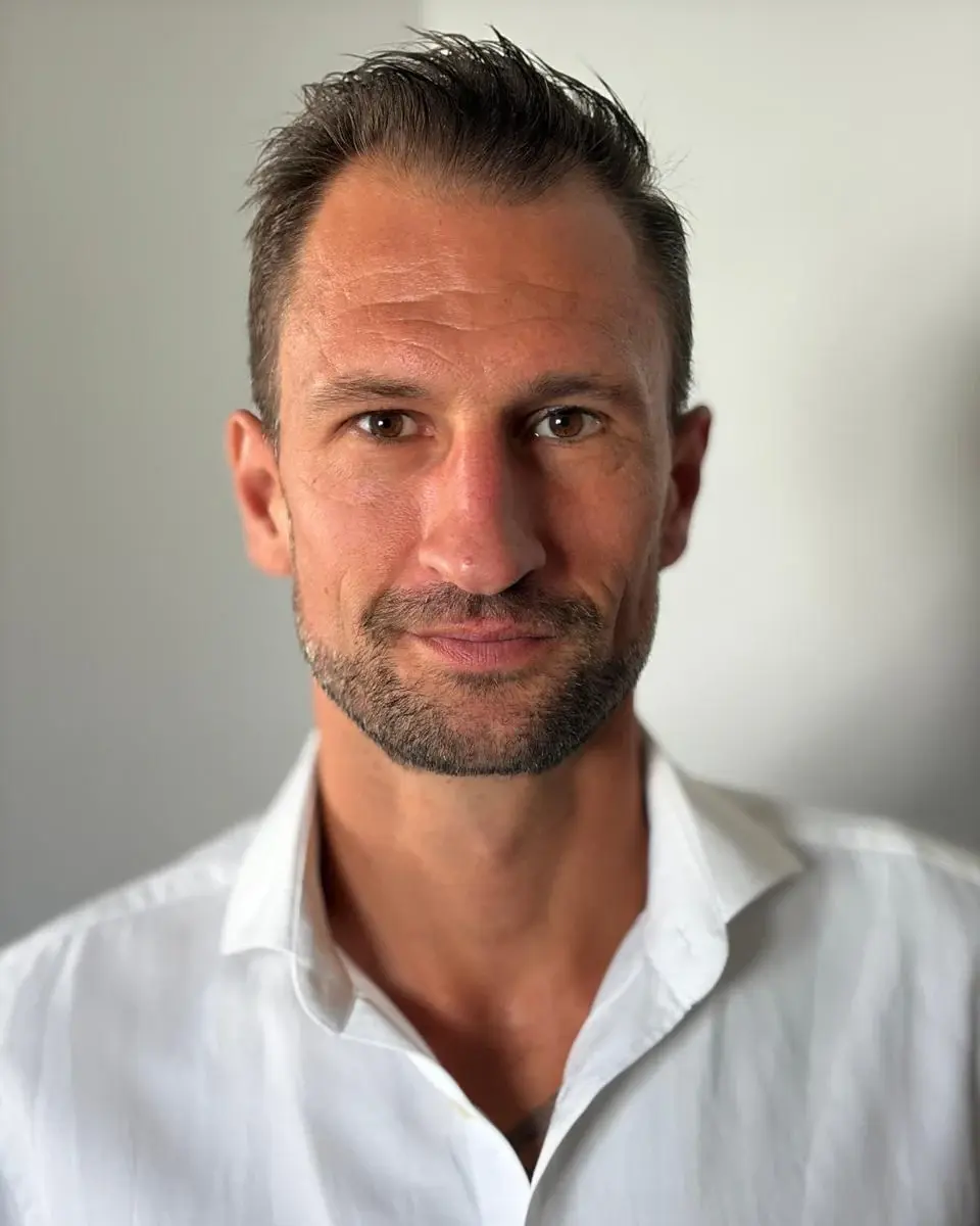 Porträt: Ihr Ansprechpartner Daniel Braun im weißen Hemd vor hellgrauem Hintergrund